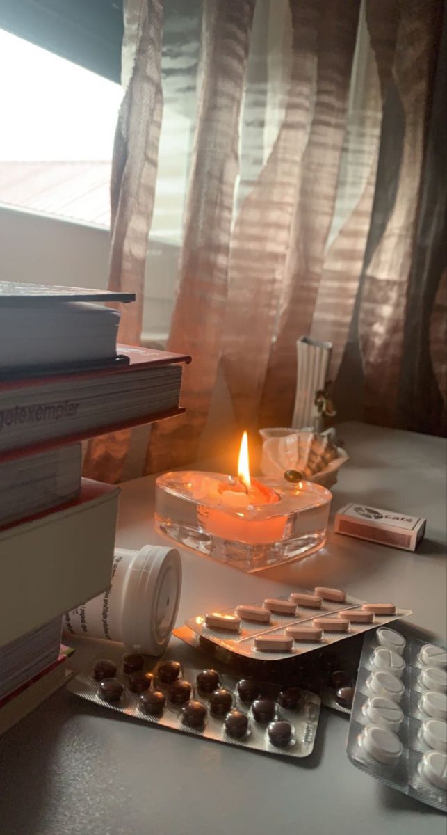 Blísteres de pastillas sobre un escritorio junto a unos libros